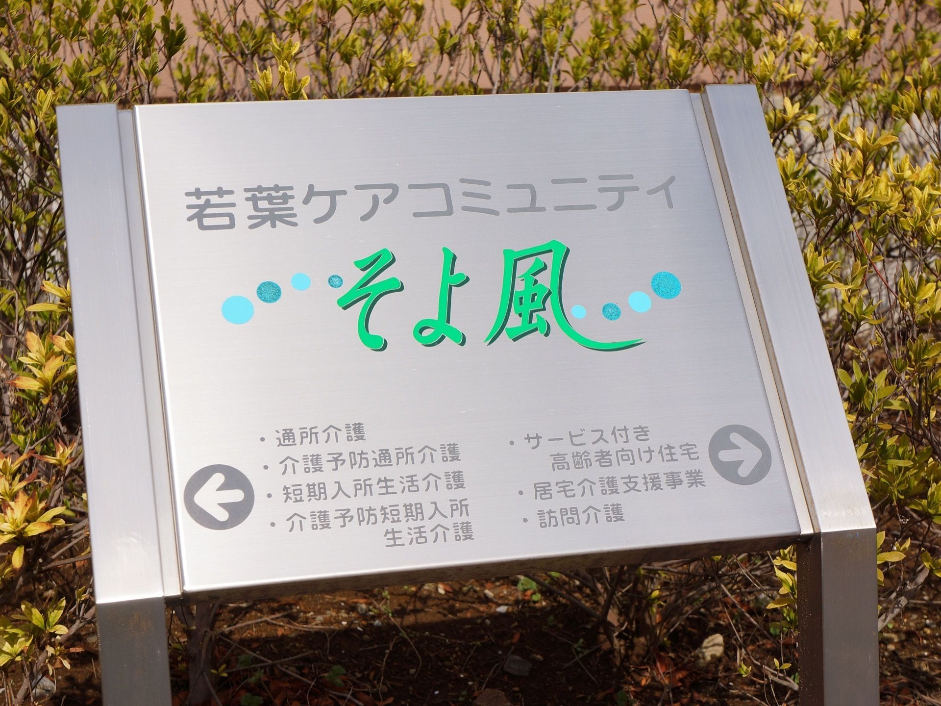 敷地出入り口付近の植え込みに看板が設置されている。施設名や各種事業名が記されており、それぞれのサービスを行っている方向を矢印が指名している。