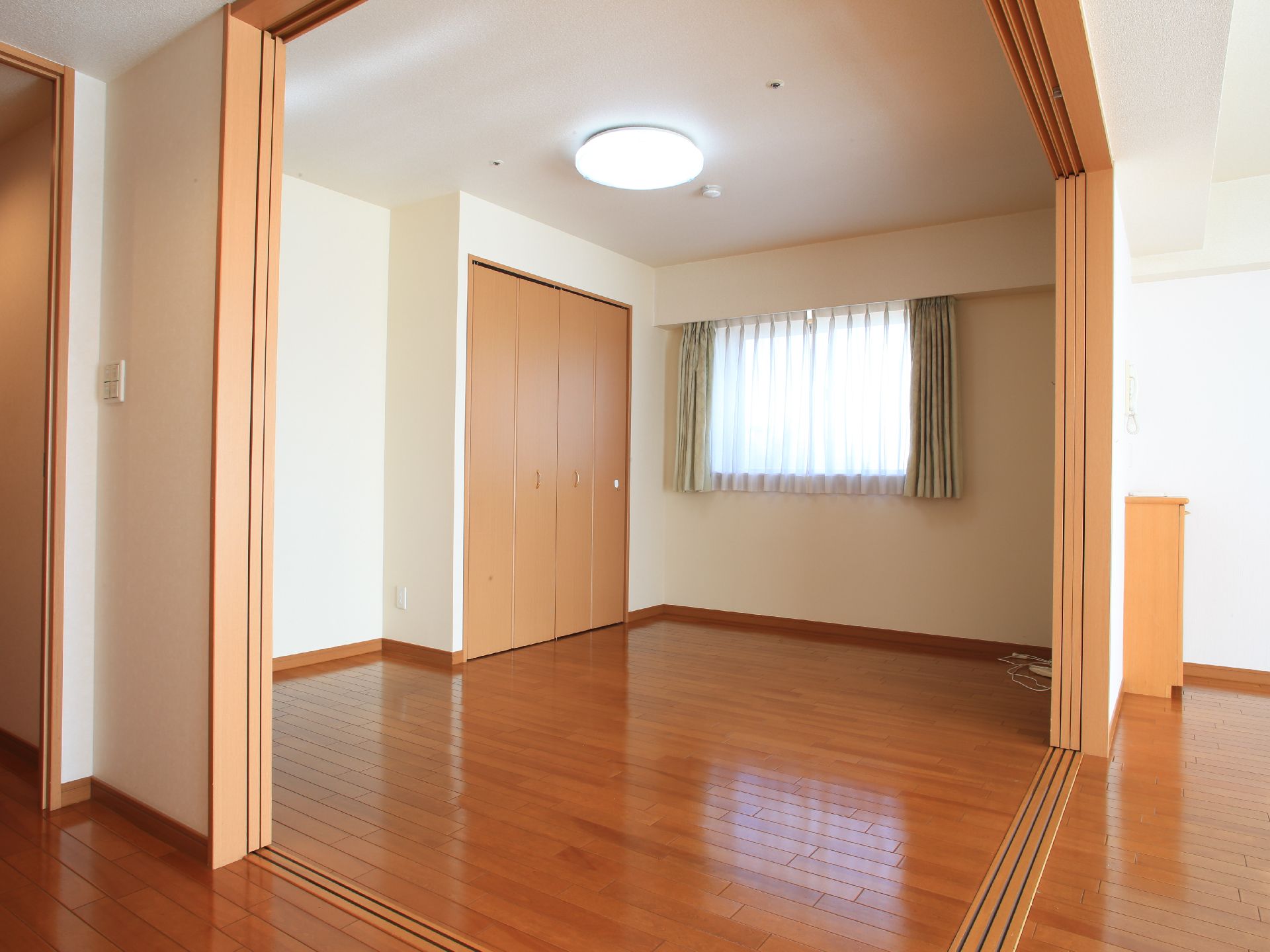入居者様の居室の寝室部分。窓があり、クローゼットが備えつけられている。壁の角部分が大きく開放され、オープンな間取りになっている。