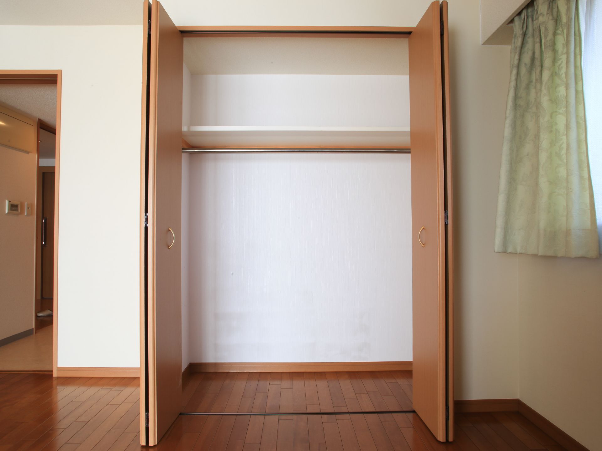観音開きのドアがついた、大きなクローゼット。衣服を吊るす棒が渡されている。上部分が仕切られ、物を置けるようになっている。