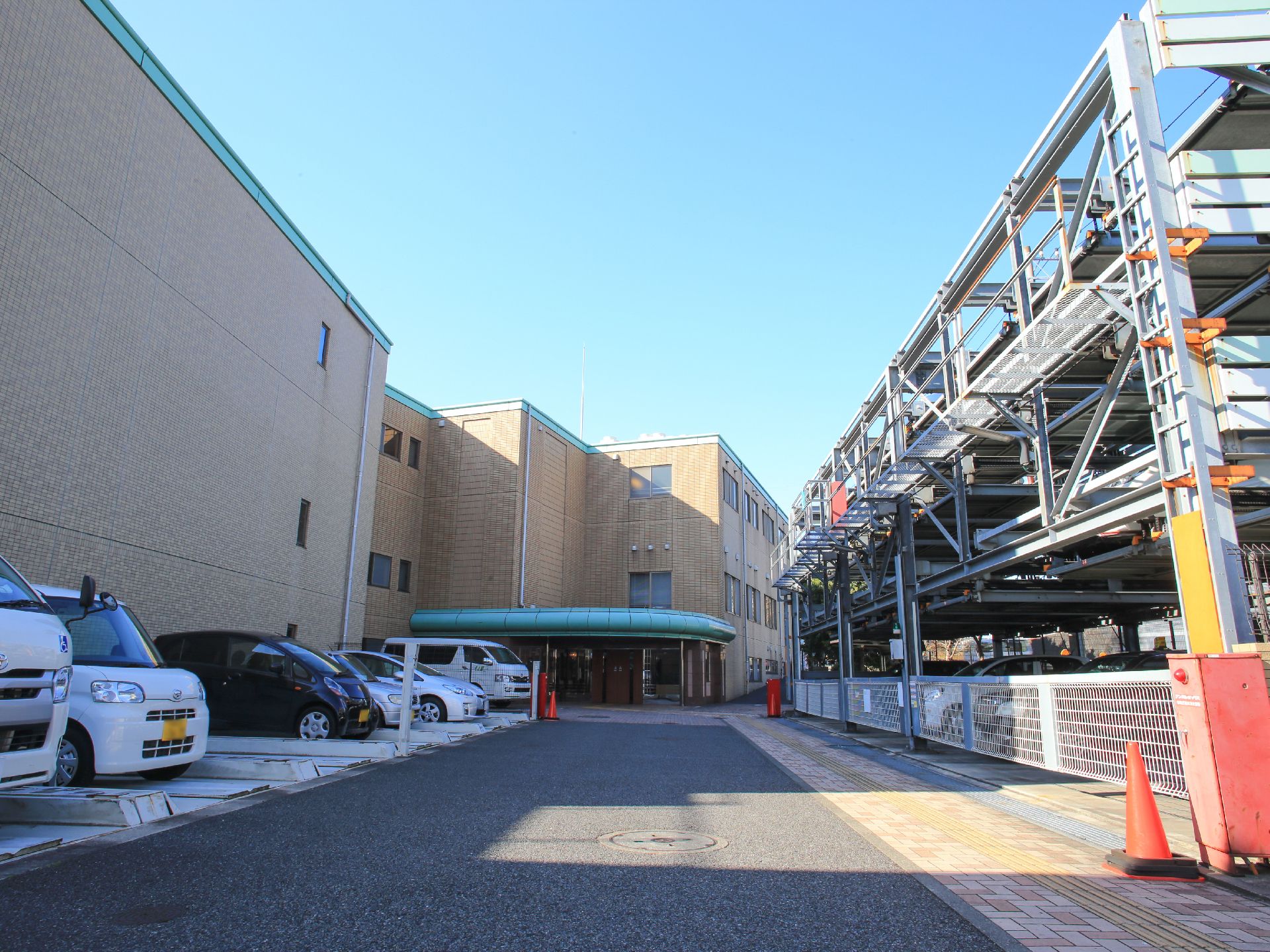 建物の側に駐車スペースが用意されている。１台分ずつスペースが区切られている。玄関の手前には施設車両が止められている。