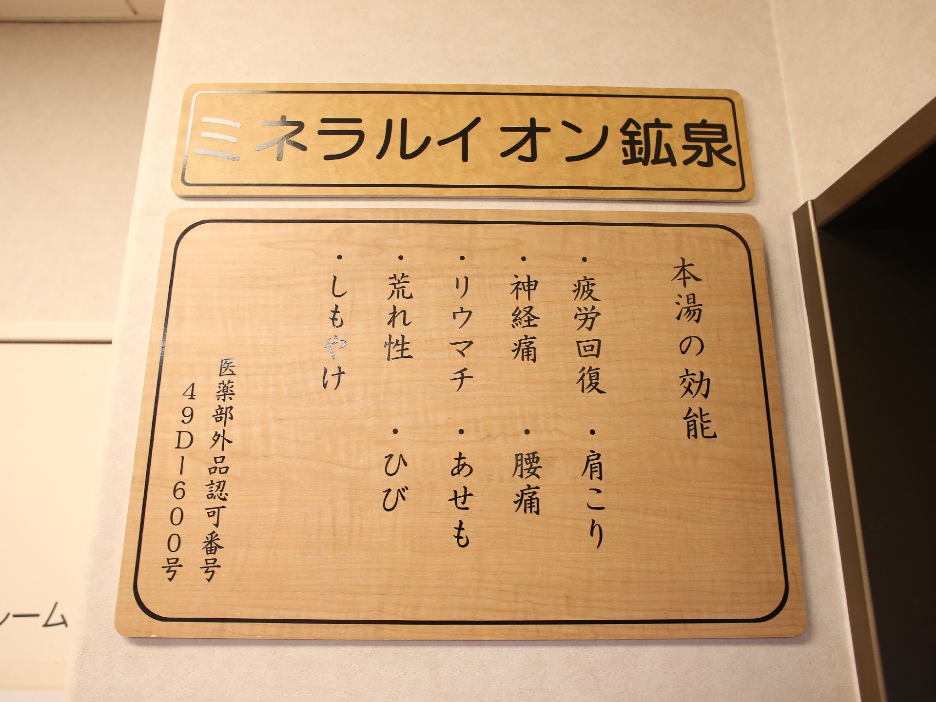 お湯の効能が書かれたプレートが壁に取りつけられている。ミネラルイオン鉱泉で神経痛やリウマチにも効果がある。