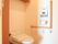 Ｌ字形の木製手すりが設置されたトイレである。壁には温水洗浄機能のリモコンや緊急呼び出しボタンも備えつけられている。