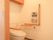 収納棚を備えた洋式のトイレである。Ｌ型、可動式タイプの手すりが完備されているほか、ナースコールもある。