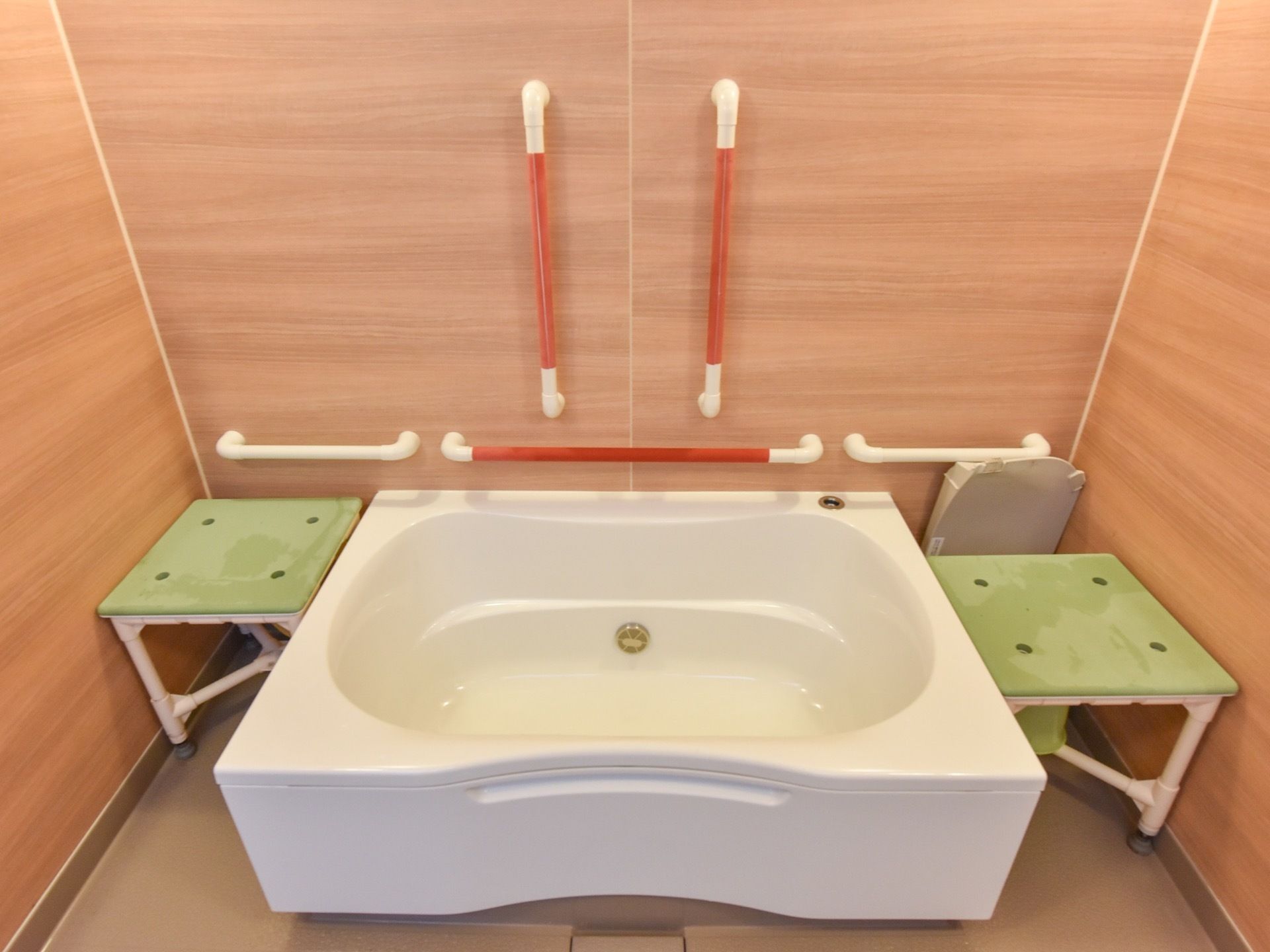 木目調のクロスを採用した浴室は、木のぬくもりを感じながら入浴をお楽しみいただける空間である。横側の壁に手すりを完備している。