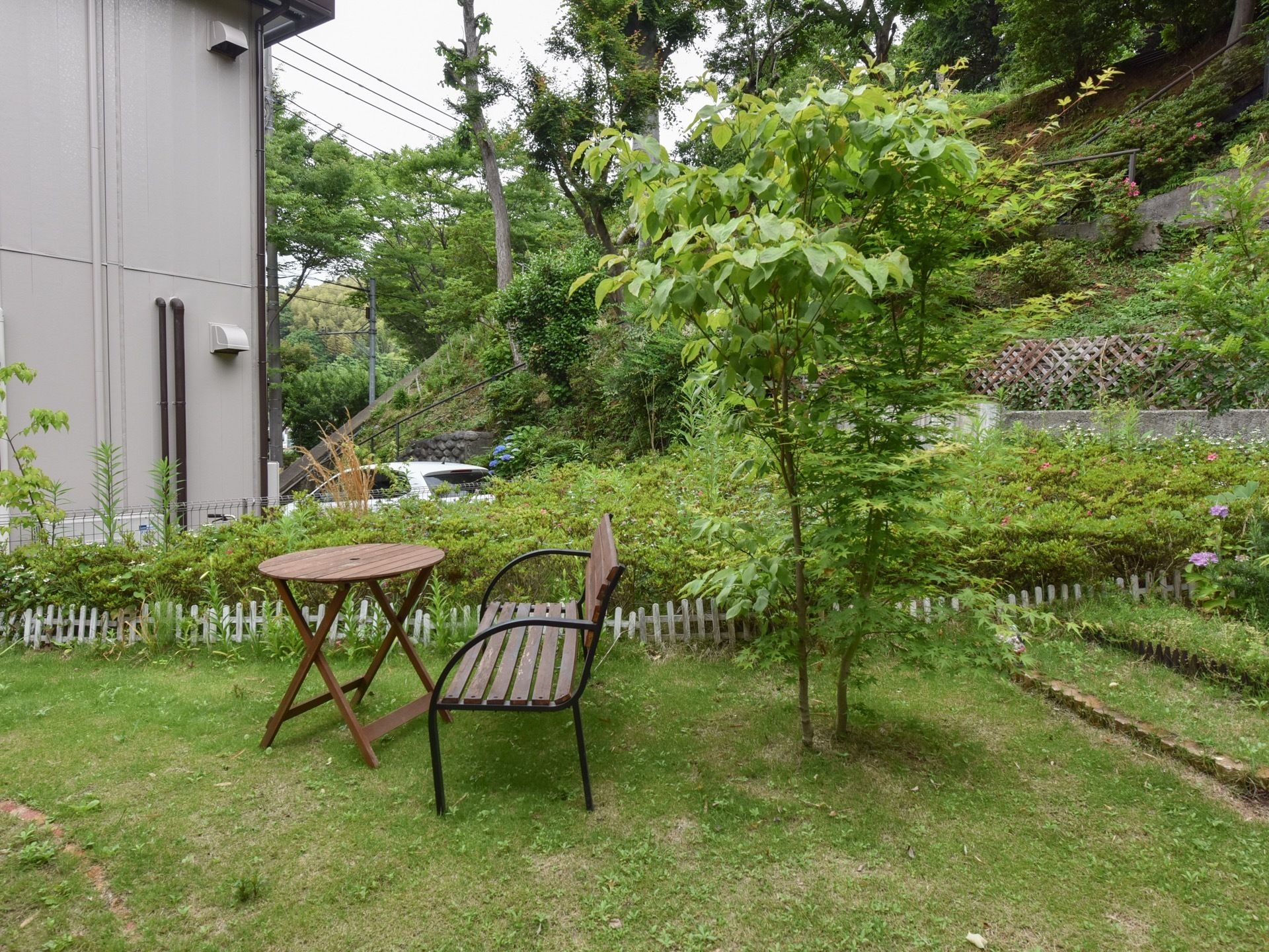 緑に囲まれた、閑静な住宅街の中にある施設の庭である。緑の芝生の上に木製テーブルとベンチが一対置かれている。