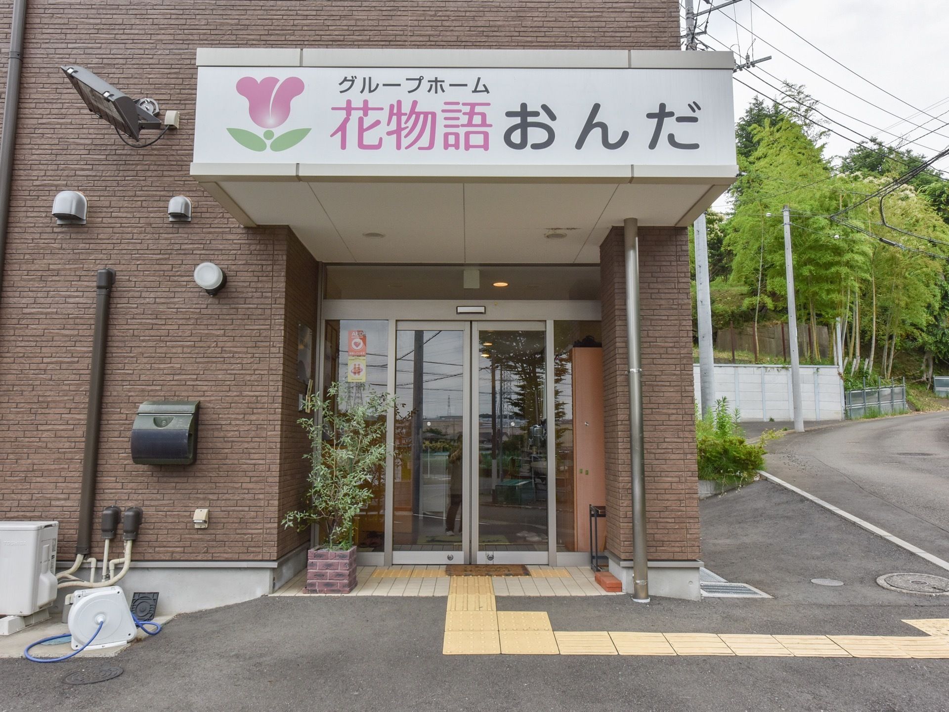 道路からすぐの位置に玄関を設けている。ガラス張りの自動ドアの傍に、レンガ造りの鉢に植えた樹木を飾っている。