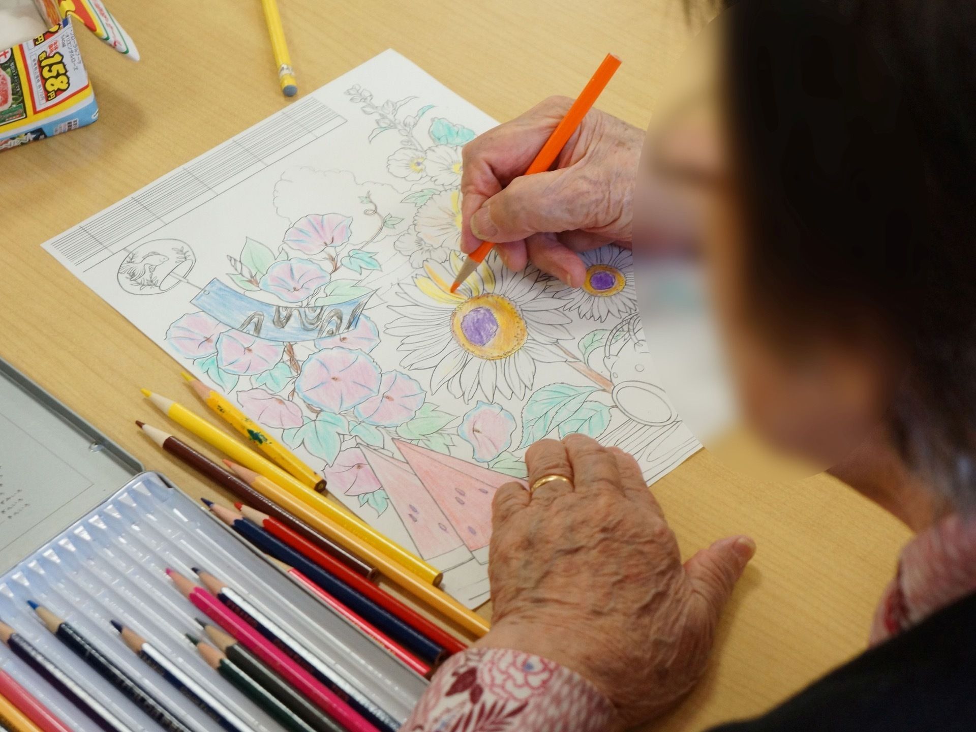 夏らしいひまわりとあさがおの塗り絵を楽しむ。色鉛筆を使い指先を使う作業。机も清潔感があり、広々としていて使いやすい。