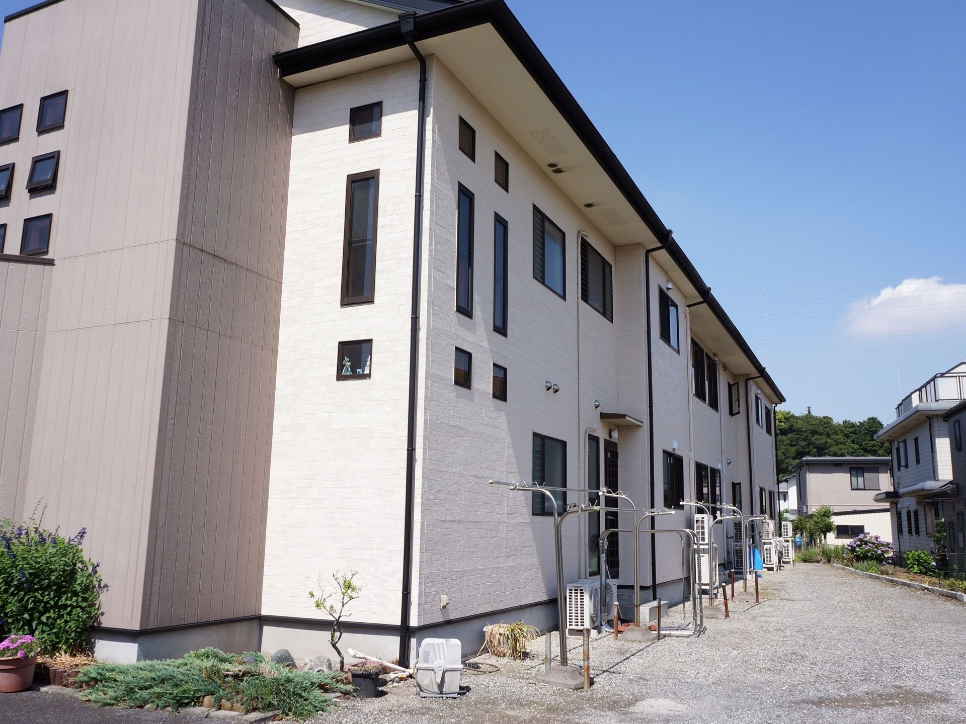 白を基調とした２階建ての建物である。砂利が敷かれた日当たりの良いスペースに、物干し竿が並んで置かれている。