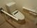 白を基調とした個室トイレである。便器横には手すり、壁には、台が付いた２連のペーパーホルダーが設置されている。