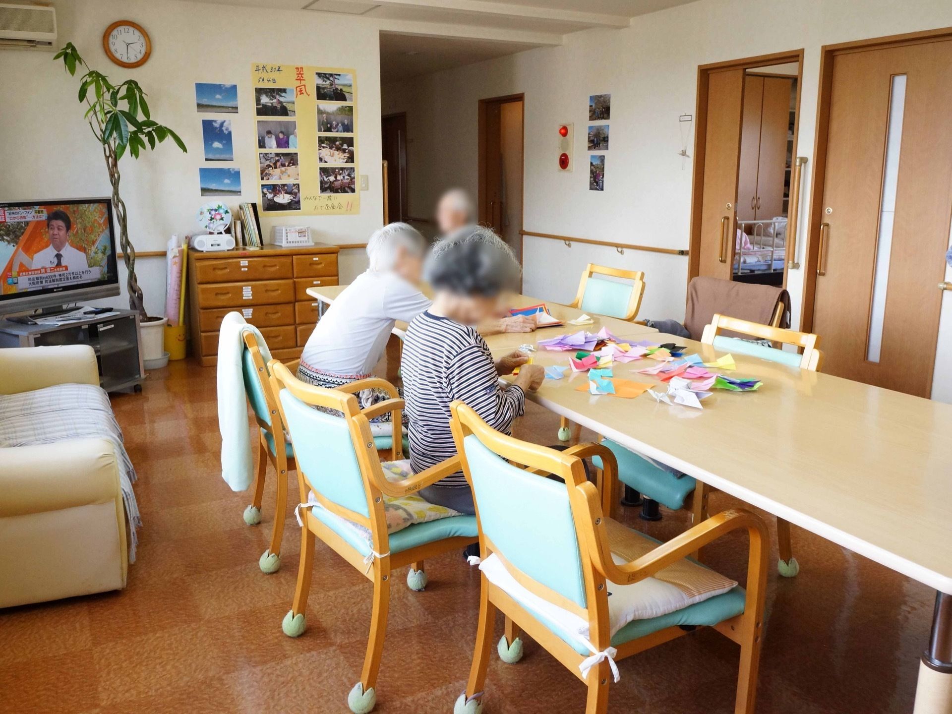 ダイニングテーブルと脚にテニスボールが取り付けられた椅子が置かれている。壁には写真が複数飾られている。
