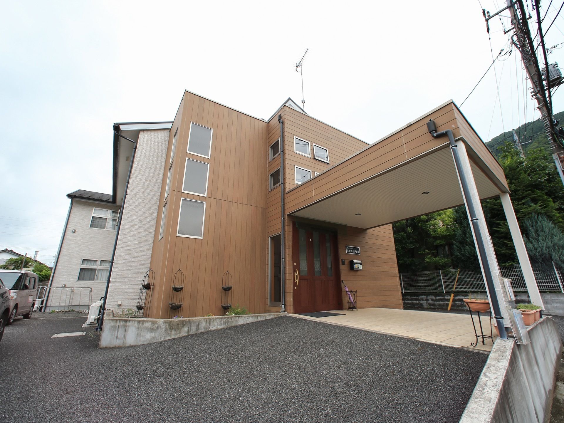 施設の正面部分の壁は木の素材になっており、後ろの部分は白い壁になっている。駐車場から玄関へ続くところはスロープになっている。
