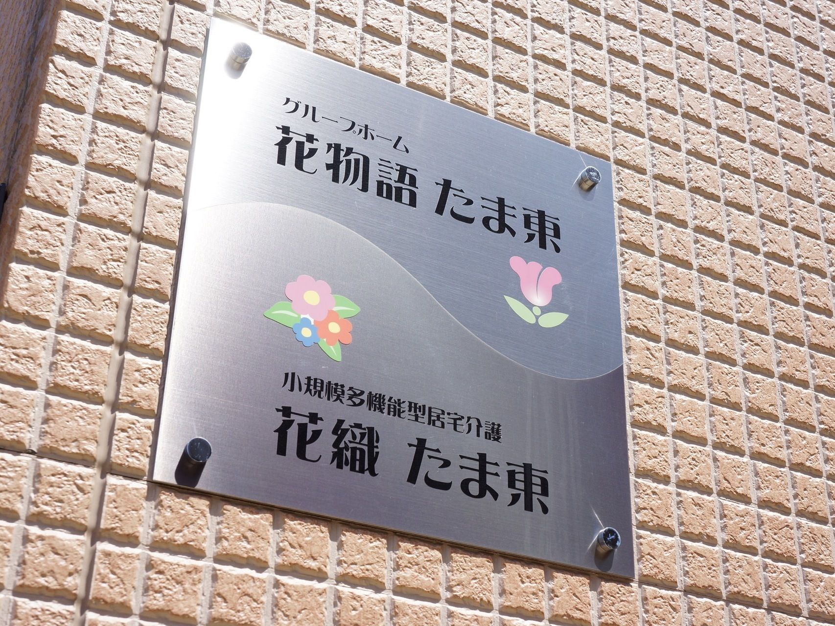 施設の看板は、シルバープレートになっており、読みやすい黒い字で施設名が書かれ、可愛らしい花の絵が描かれている。