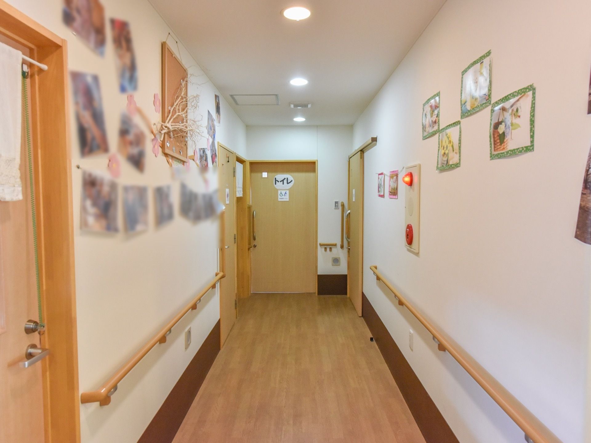 壁面に季節の飾りや写真などがある廊下の突き当たりに設置されたトイレ