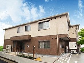 木目調の玄関扉と壁や庭のタイル部分が洋風建築を思わせる２階建ての施設
