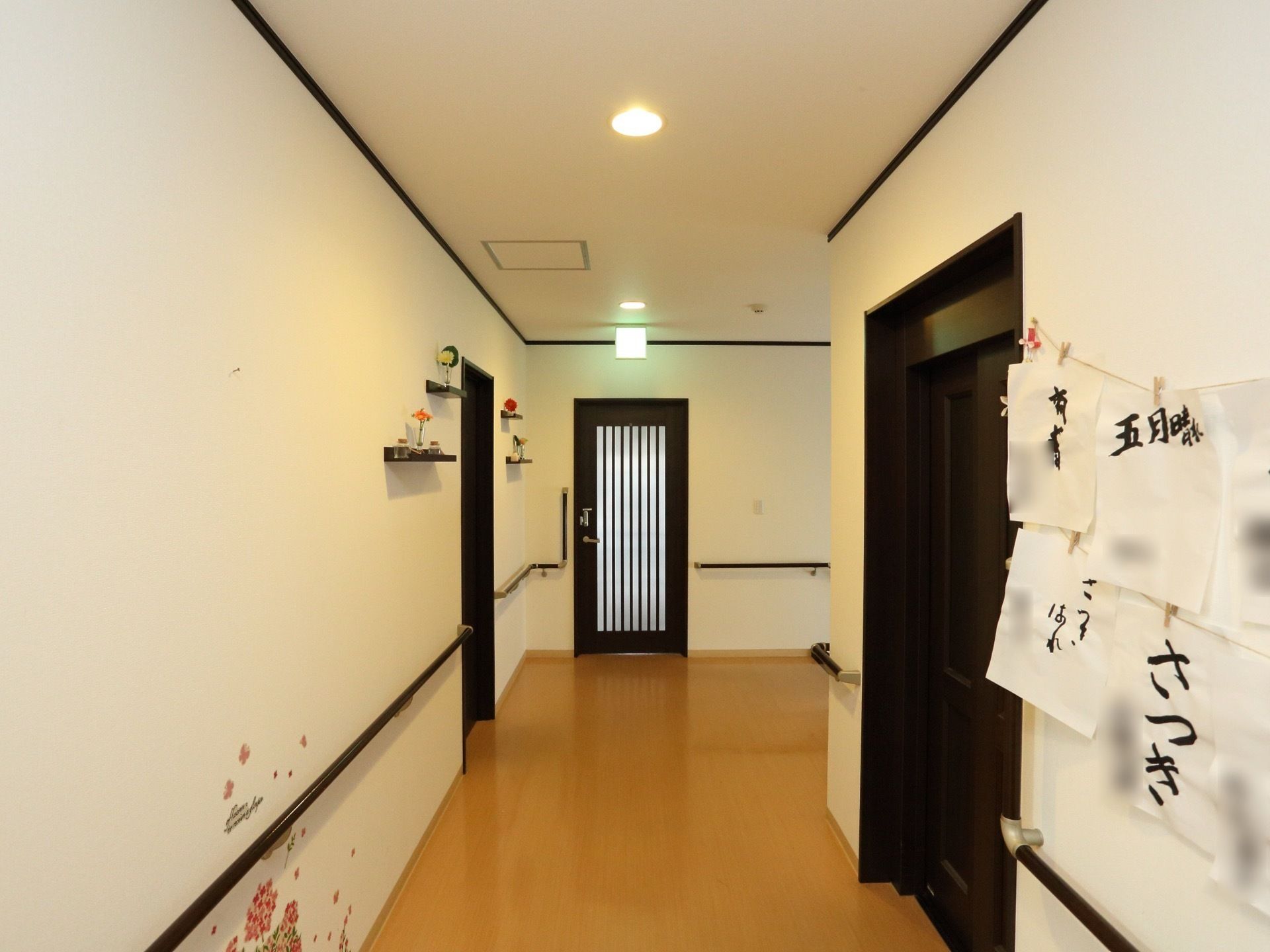 白い壁に濃い茶色の扉や手すりがついた広々とした廊下