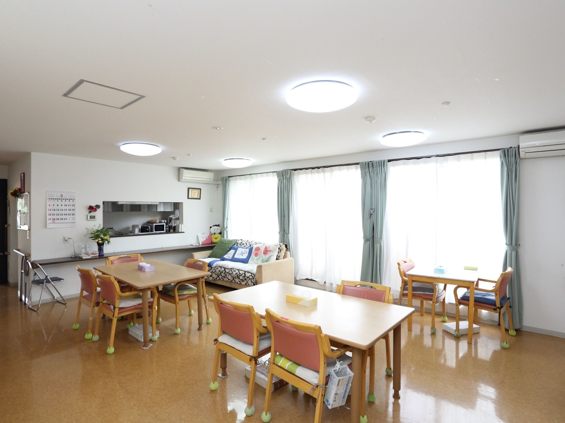 広い一室に、椅子やテーブルが並べられている。台所も設置されており、窓から日差しが入り、部屋があたたかい雰囲気になっている。