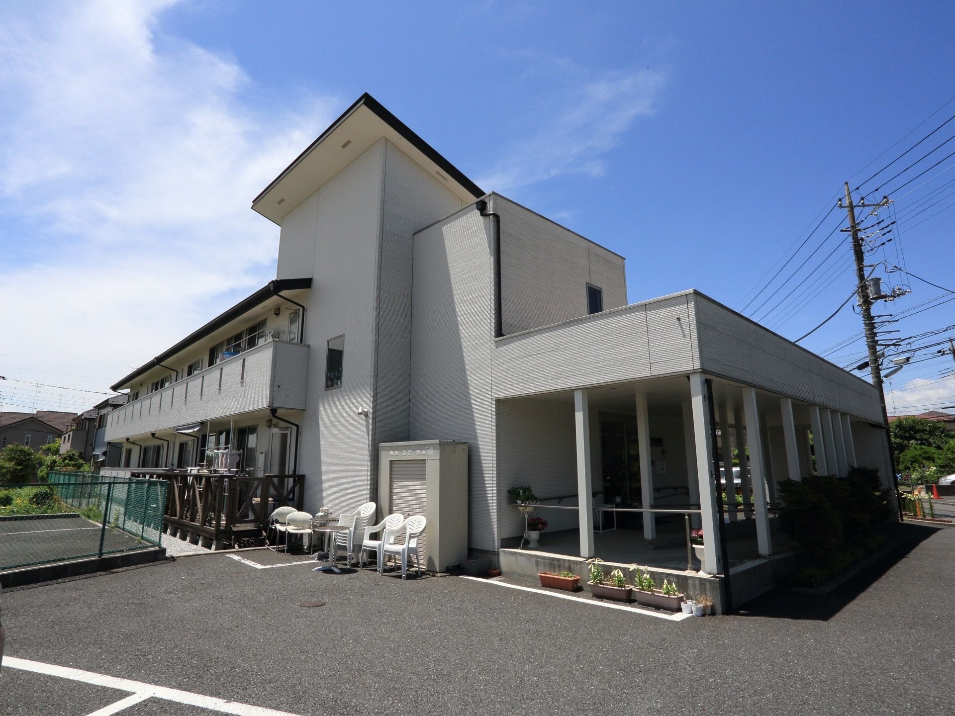 白い２階建てのグループホームである。各部屋にはベランダが設置されており、１階部分にウッドデッキがある。