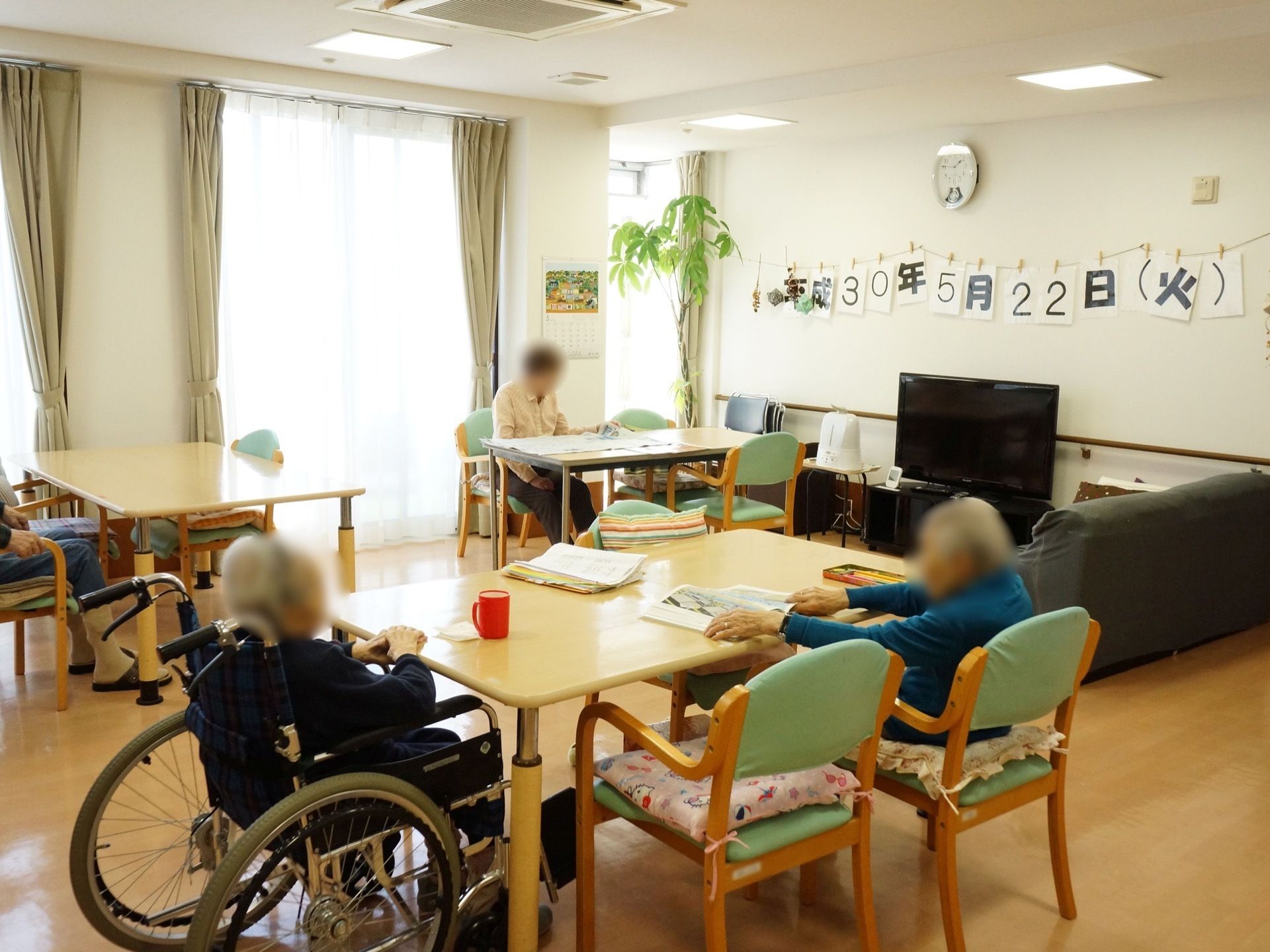 共有スペースには、ゆったりと間隔を置いてテーブルセットを並べている。壁際にテレビを備え、傍にソファを置いている。