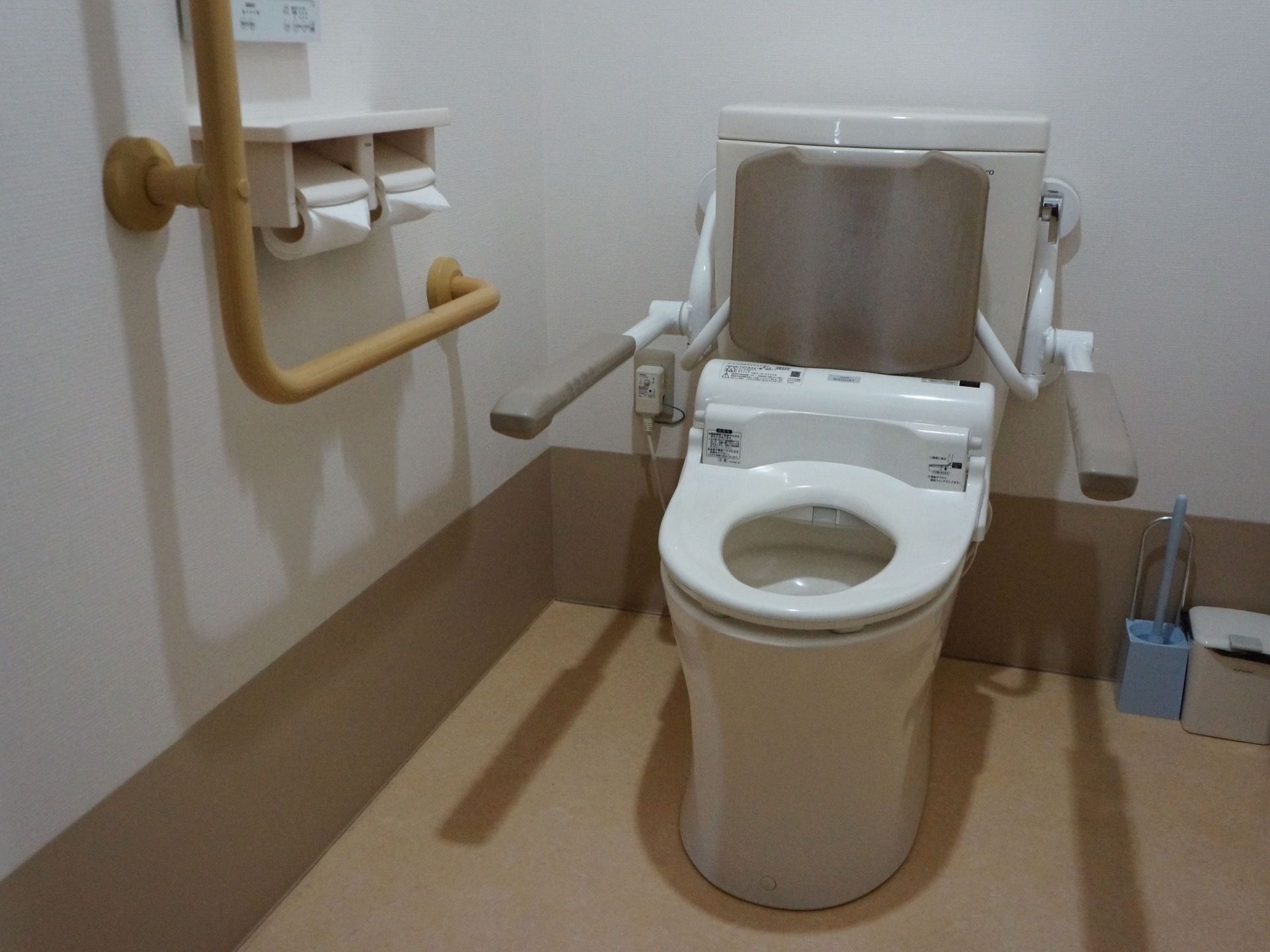 手すりと背もたれと肘置きの付いた多機能トイレである。スペースが広くとってあり、ペーパーホルダーは二つ付いている。