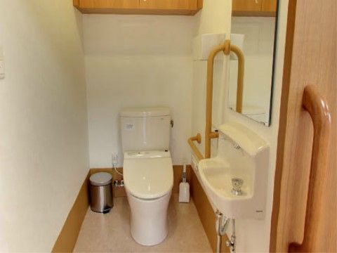 温水洗浄便座の近くには手すりが設置され、安全に使用することが可能である。壁には鏡と洗面設備も設けられている。