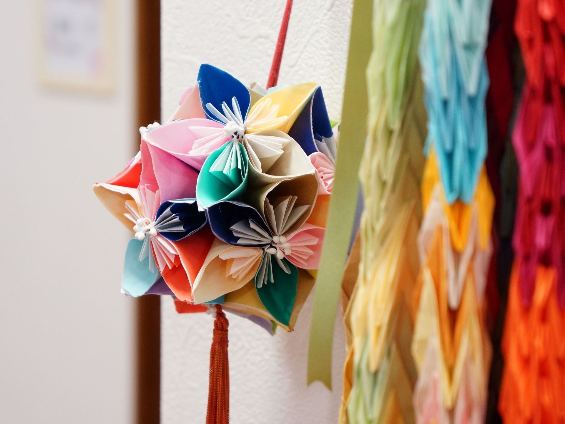 青、ピンク、緑、黄色などカラフルな折り紙を使って作られたつまみ細工の飾り物