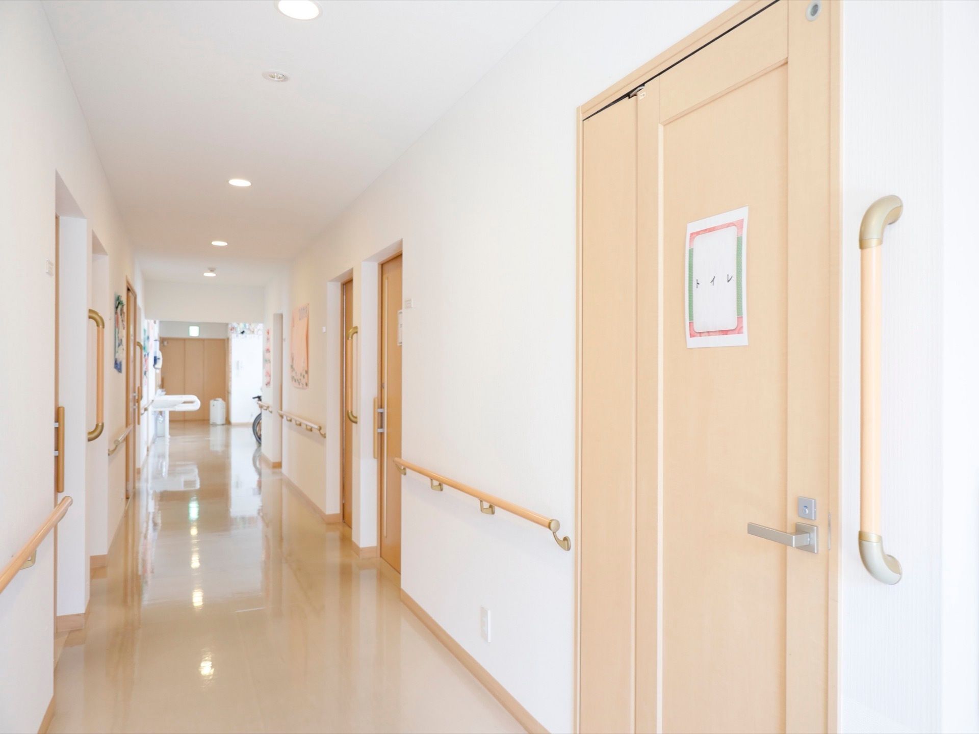 明るい色調でコーディネートされた通路である。壁の両側やトイレの出入口に手すりが完備され、安心して移動できる。