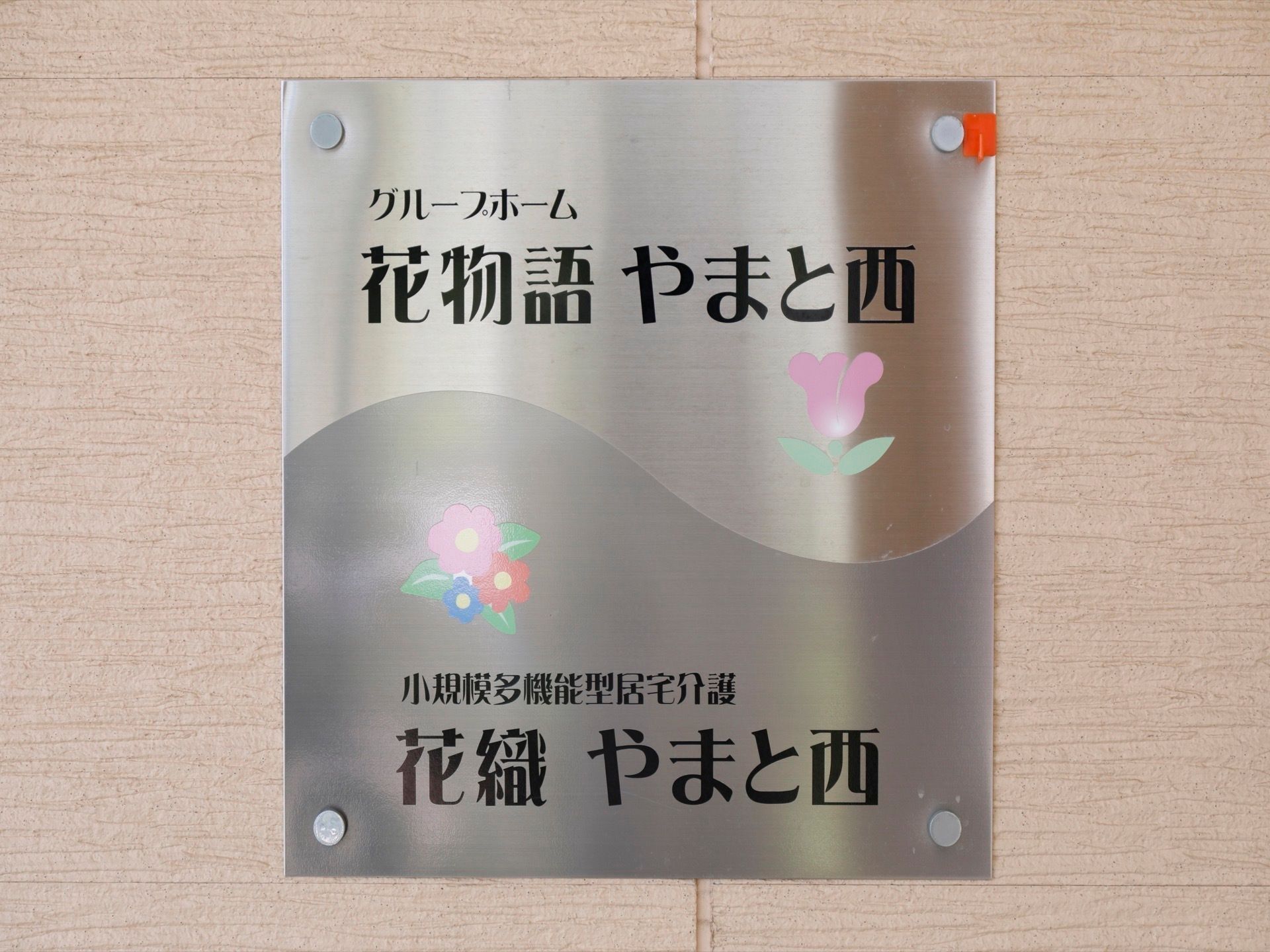 施設前の表札には、ホームの名称と介護サービスの名称とが記してある。壁にぴったりと取り付けた、薄いプレートである。