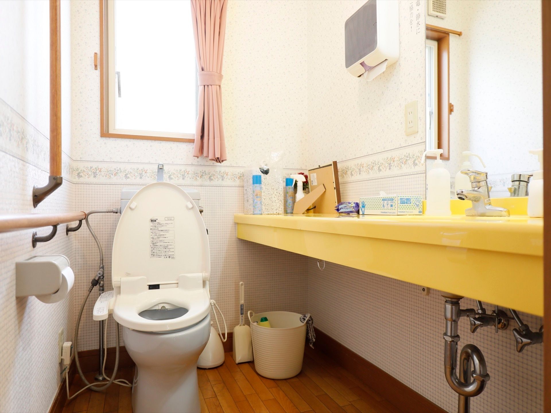 共用の個室トイレ。小物置きになっている黄色い棚は手洗い用の水道と一体になっている。下のスペースに掃除用具がある。