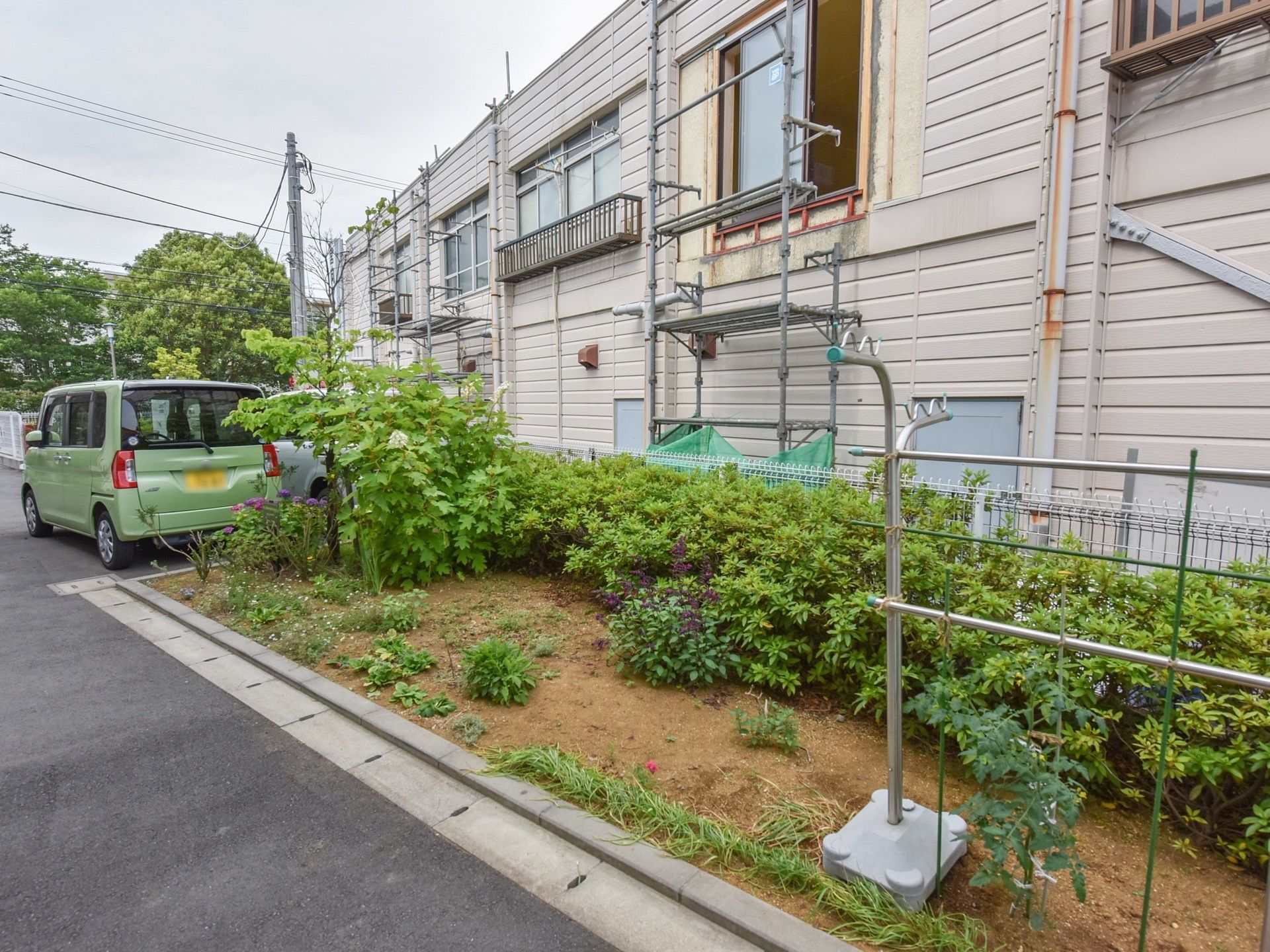 敷地内の一角に赤土を取入れ、さまざまな草木や樹木を植え付けた緑豊かな花壇を設けている。中に洗濯干竿を置いている。