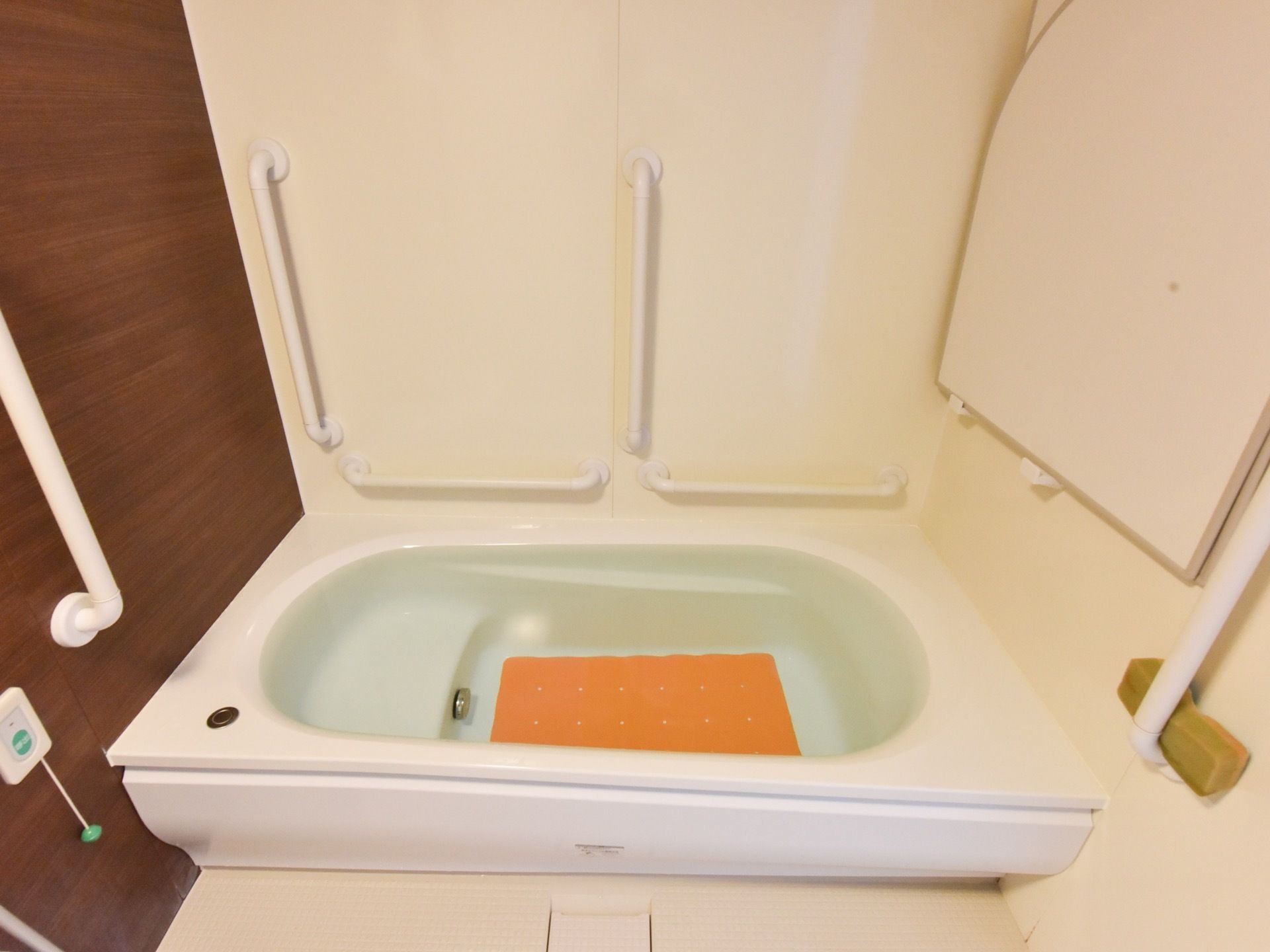 お一人が、ゆっくりと入浴タイムをお楽しみいただける広さのユニットバスである。壁に縦と横の手すりを設置し、バスタブの中に段を設けている。