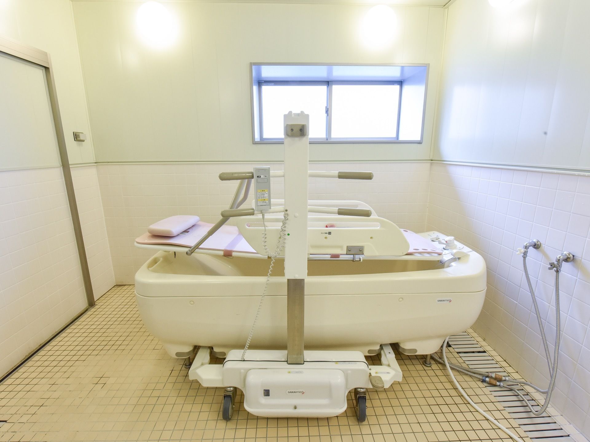 白を基調とした機械浴を備えた浴室は、清潔感のあるイメージである。横側に小さな窓を設け、光が射し込み明るい空間も設けている。