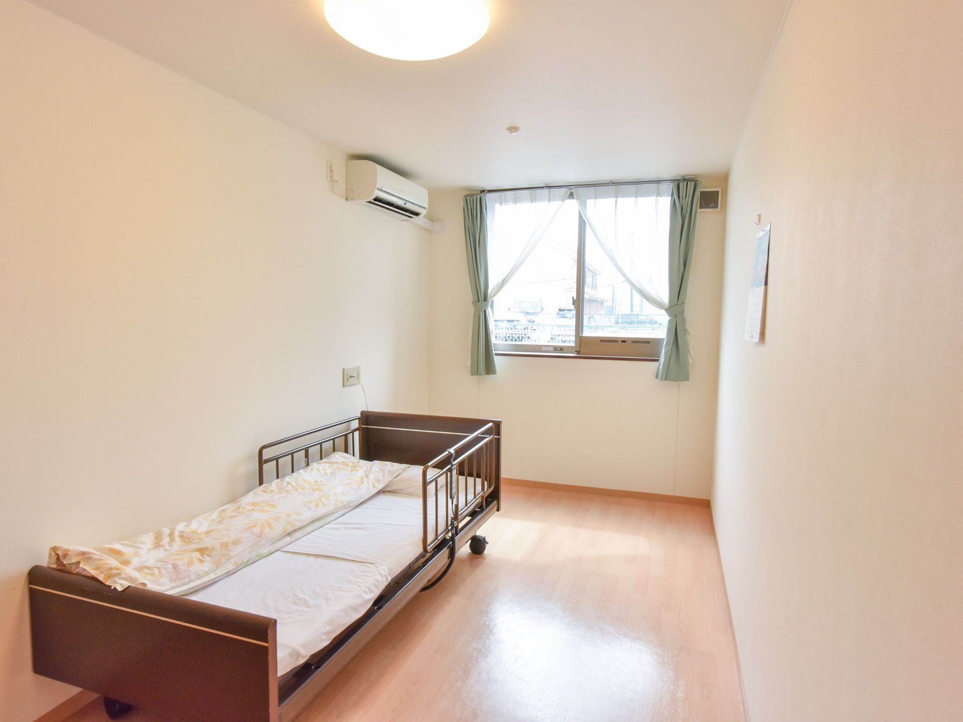 光が射し込む日当たりの良い居室である。壁際に介護用ベッドを備え、エアコンを完備しているので、室内は快適な温度を保つことができる。