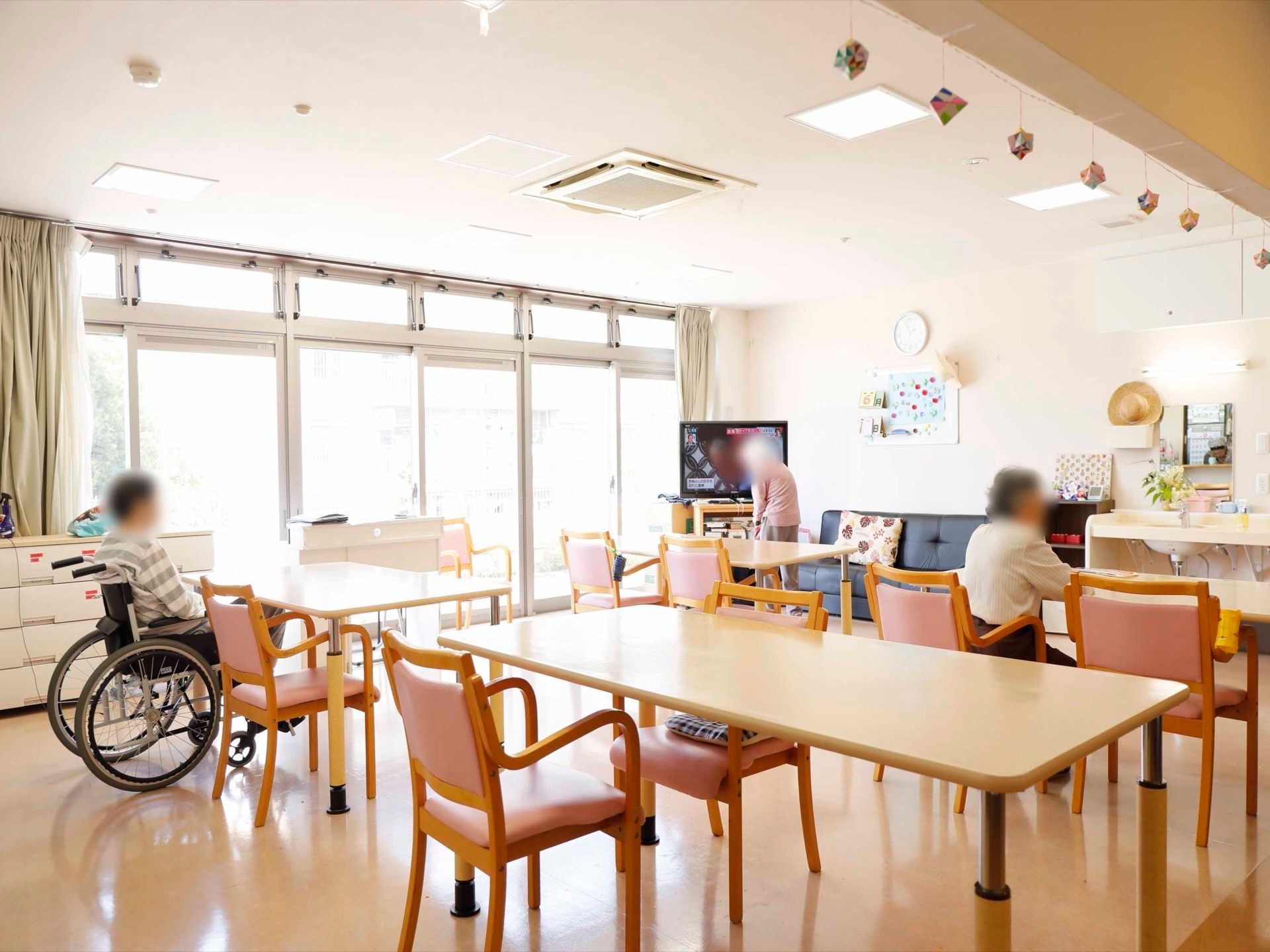 テレビやソファ、ダイニングテーブルなどが置かれている。椅子は薄いピンク色の座面である。正面の壁に鏡のある洗面台も備わっている。