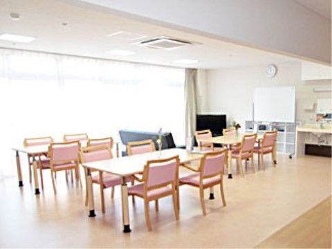 ４人掛けのテーブル、ソファ、テレビなどが置かれた日光が差し込む明るいリビングルーム