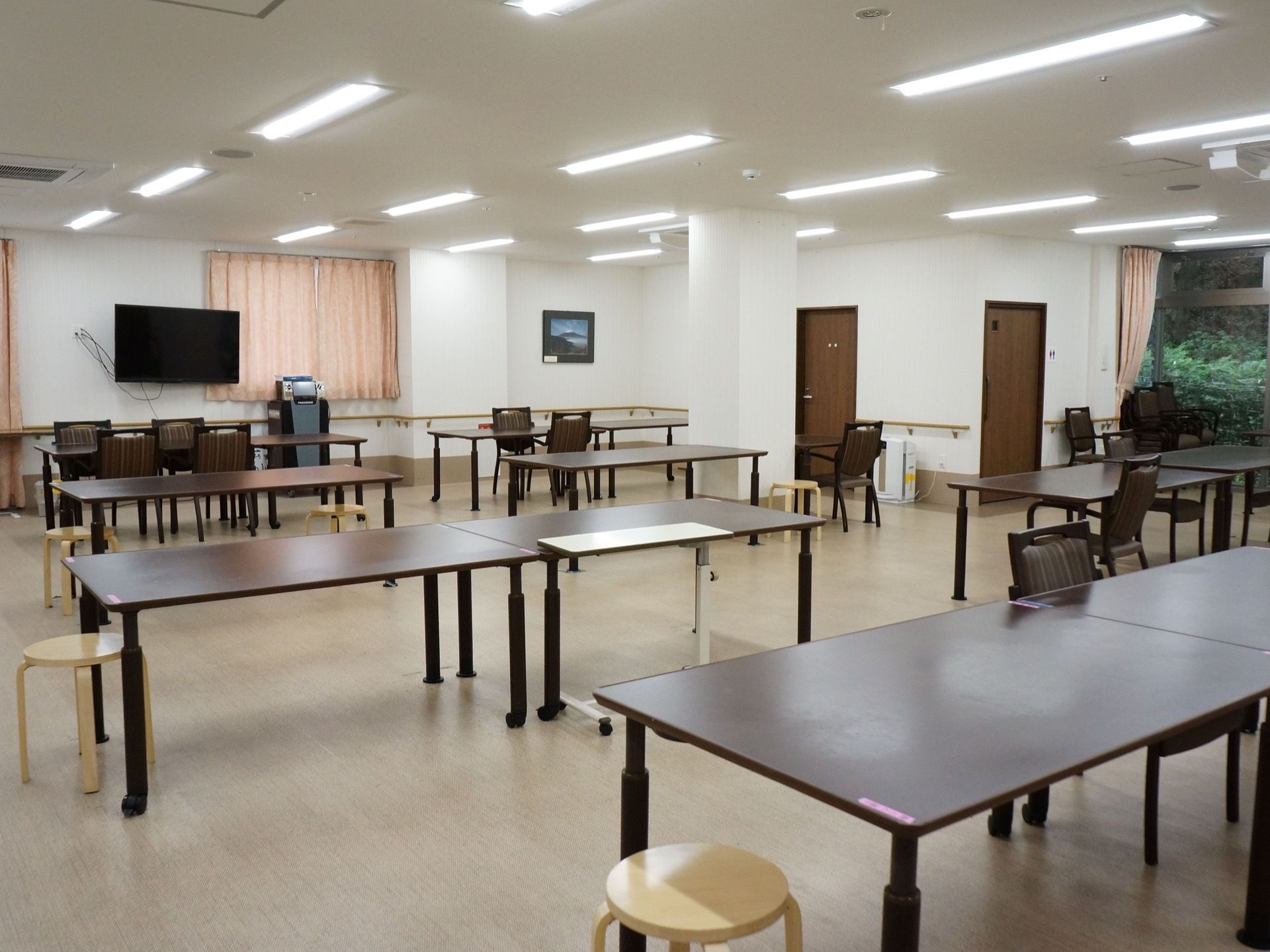 広々としたスペースの食堂では、４人掛けのテーブルを２卓寄せてセッティングしている。壁にテレビを備え、カラオケの設備も整えている。