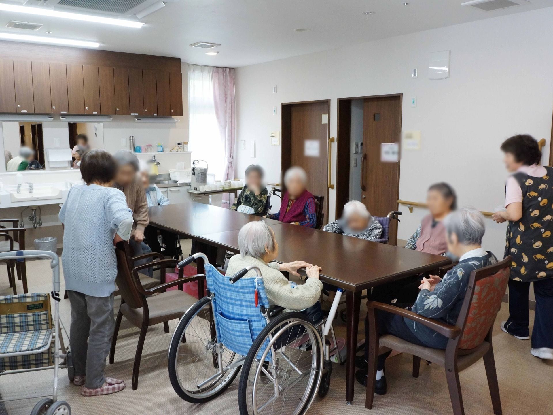 洗面台と簡易キッチンがあるリビングルームで会話を楽しむ入居者