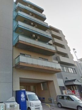 1階が駐車スペースになっていて、その横に自動販売機が設置された6階建てのビル