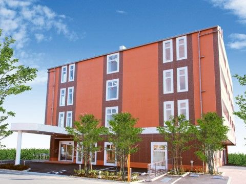 サービス付き高齢者向け住宅リハビリふくや高津館の外観。赤と茶色の外壁が西欧的な雰囲気を醸し出している施設外観。大きなエントランスルーフがついています。