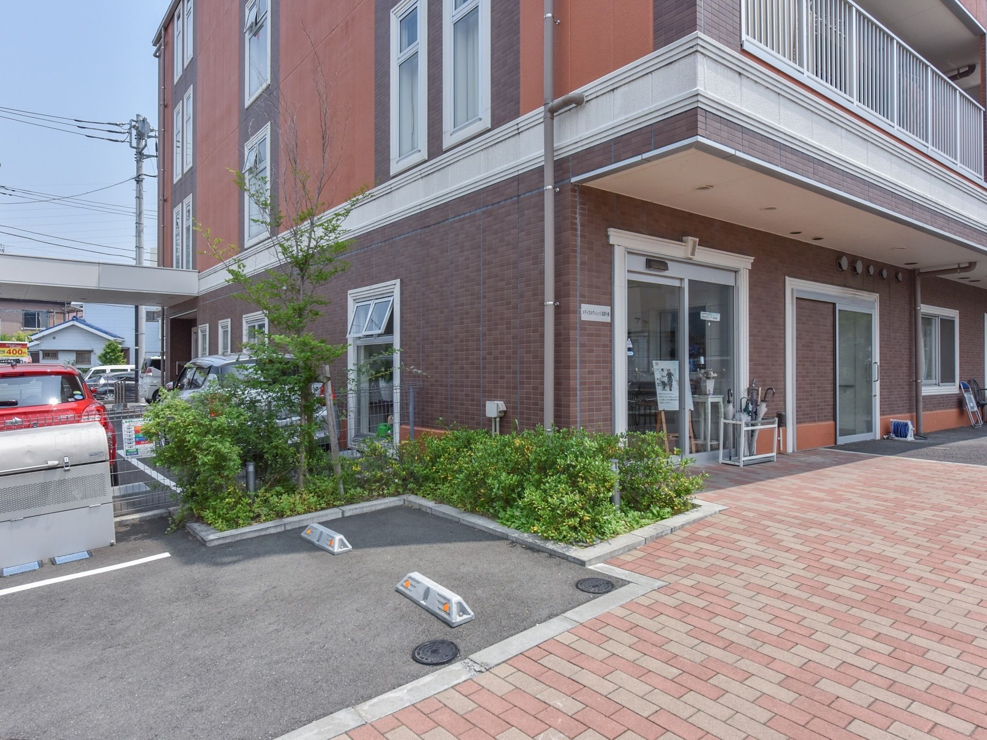 建物の道路と面した箇所にも草木が植えられている。施設の入口となる自動ドアまでは、カラフルな石畳が敷かれている。