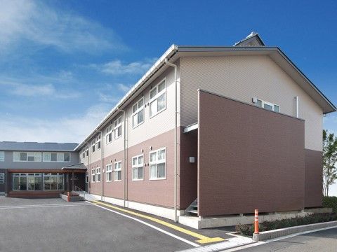 奥行きをとって駐車スペースが作られた明るいベージュと茶色の2階建ての施設