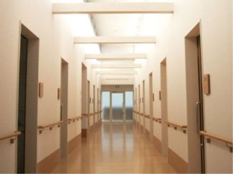 居室が並ぶ廊下。両側に手すりが設置されている。高い天井に梁が横切るデザインがとてもおしゃれな印象を与える。