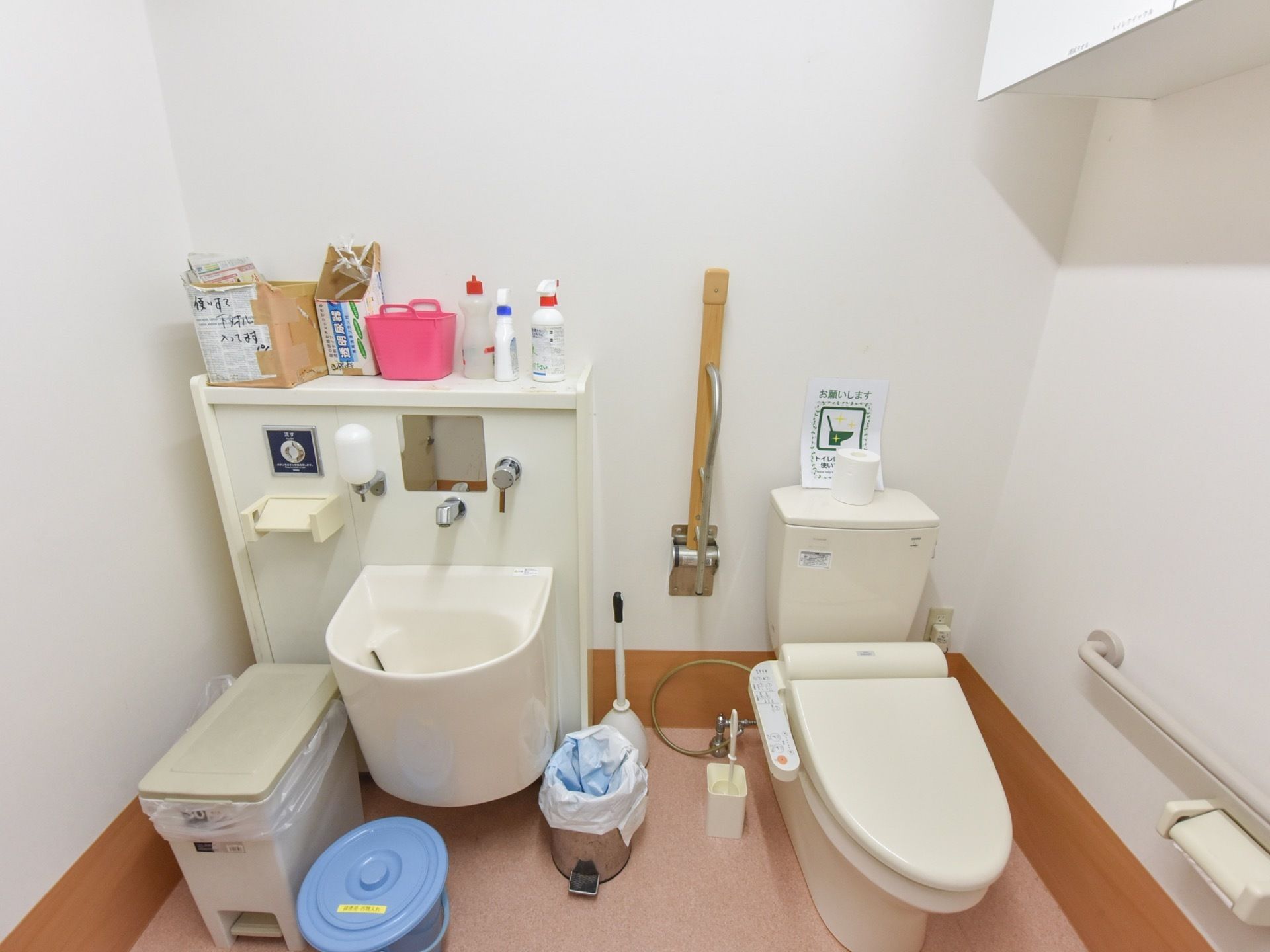 広々としたトイレはオストメイト対応である。可動式とＬ型の手すり、温水洗浄便座が設置されている。ゴミ箱が置かれている。