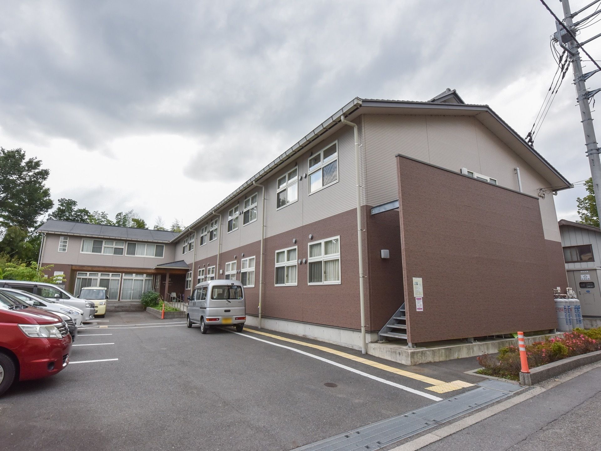 ２階建ての集合住宅のような外観の施設である。建物前に駐車場が設けられている。外階段には、目隠し用の壁が設置されている。