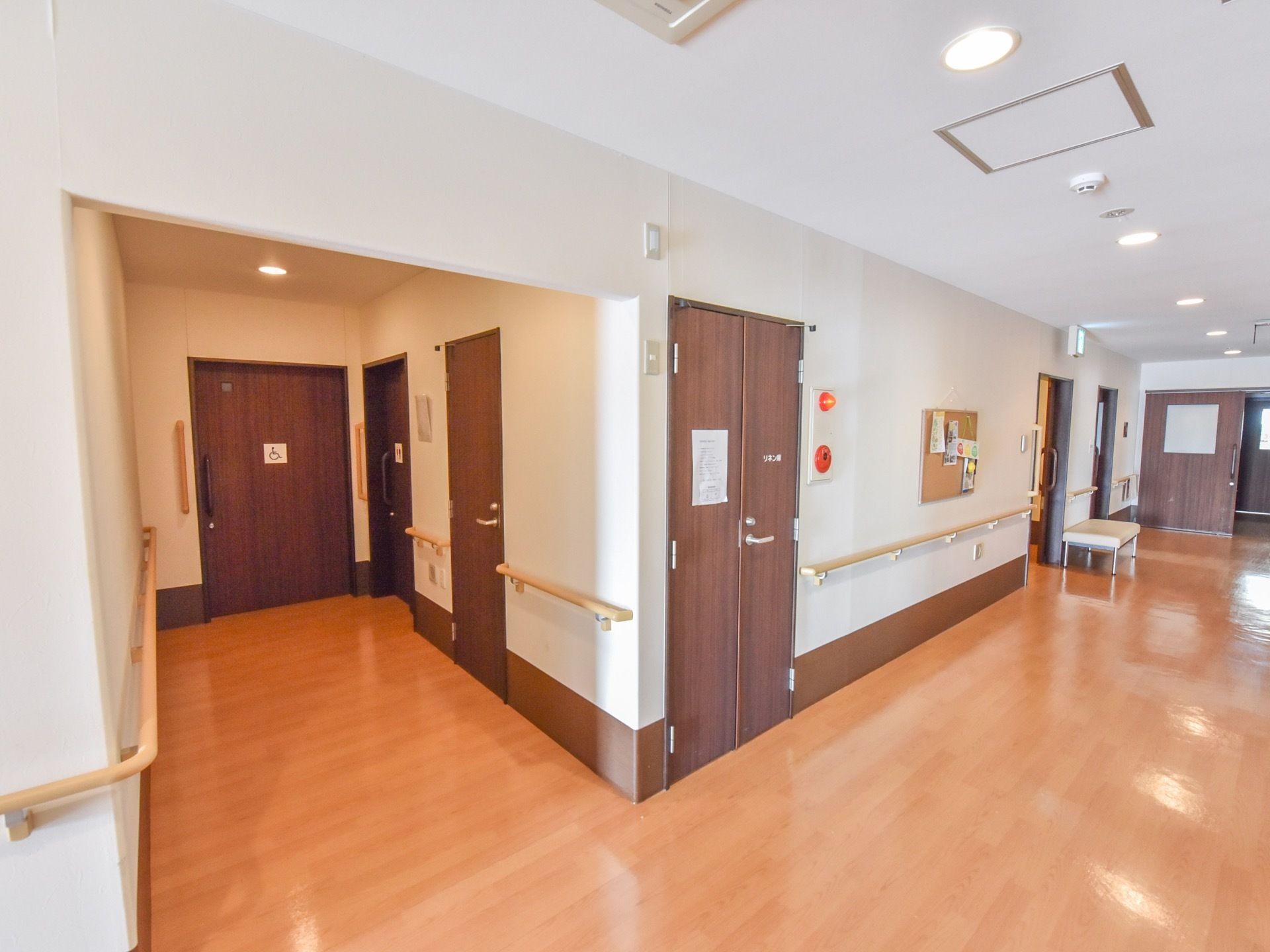 トイレへ続く通路には、腰の位置に床と並行に手すりが付いてる。トイレ入り口には垂直方向に手すりが付いている。