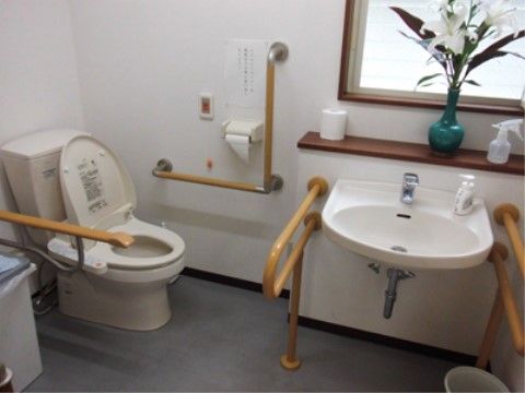 トイレは温水洗浄便座を設置しており、壁に非常ボタンを取り付けている。花瓶にヤマユリが生けられている。