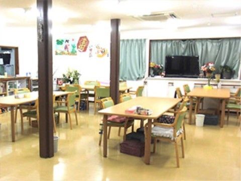 明るい配色と窓から差し込む光の中にテーブルセットが並ぶリビングダイニング