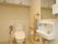 トイレの壁には、縦や横方向の手すりが設置されている。鏡の下には、壁設置式の洗面台があり、ハンドソープのボトルが置かれている。