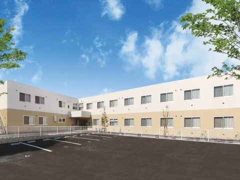 広大な駐車場が隣接する明るく落ち着いたツートンカラーをした２階建て施設