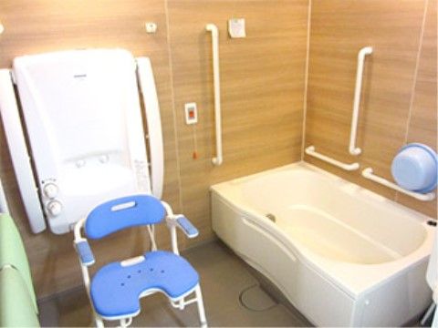 浴室の壁は木目調で温かみのある雰囲気となっている。しっかりとした介助用の椅子もあり、安心して体を洗うことができる。