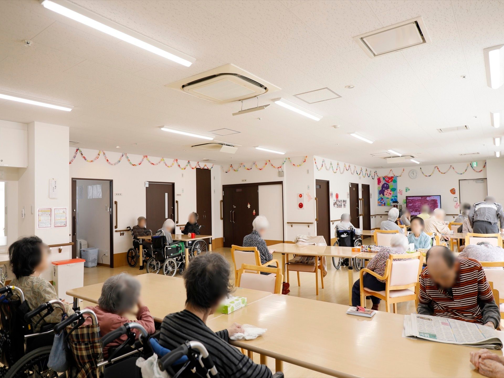 入居者様方が共有スペースをご利用している様子。会話を楽しんでいる方や一人でくつろいでいる方など、さまざまな時間を過ごされている。